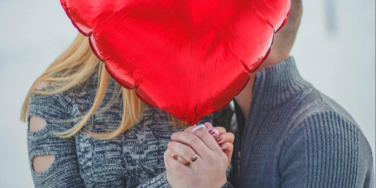 couple-holding-hands-with-red-heart-balloon